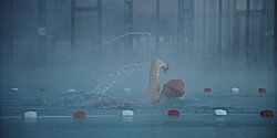 Frau schwimmt im Schwimmbad eine Bahn.