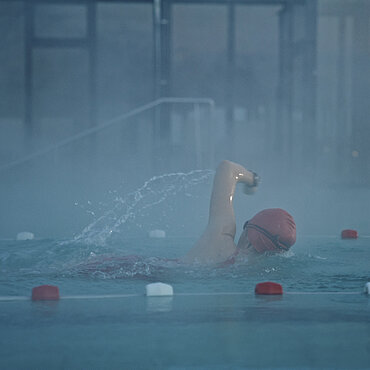 Frau schwimmt im Schwimmbad eine Bahn.