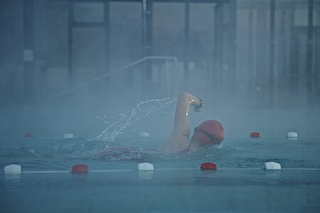 Frau schwimmt im Schwimmbad eine Bahn.
