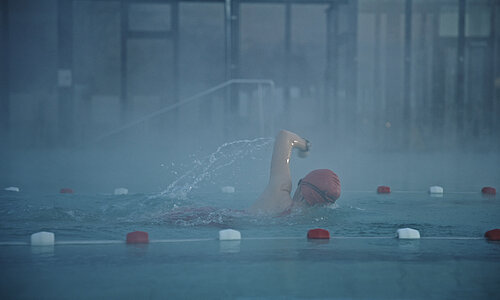 Frau schwimmt im Schwimmbad eine Bahn.