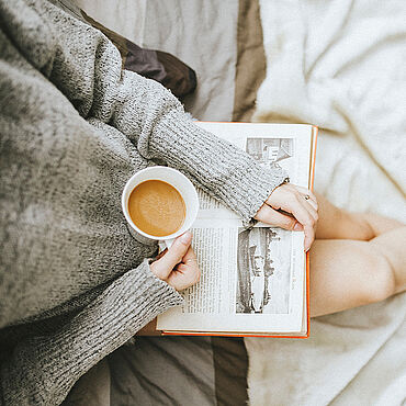 Junge Frau mit einer Tasse Tee und einem Buch