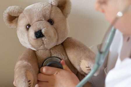 Ein Teddybär wird von einem Kind mit einem Stethoskop untersucht