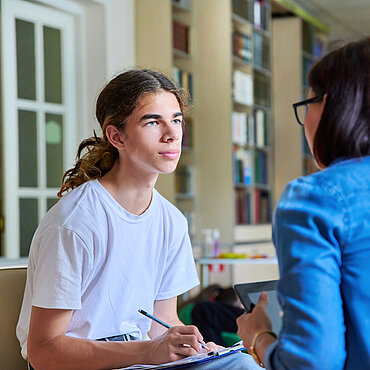 Ein Schüler spricht mit einer Lehrkraft.
